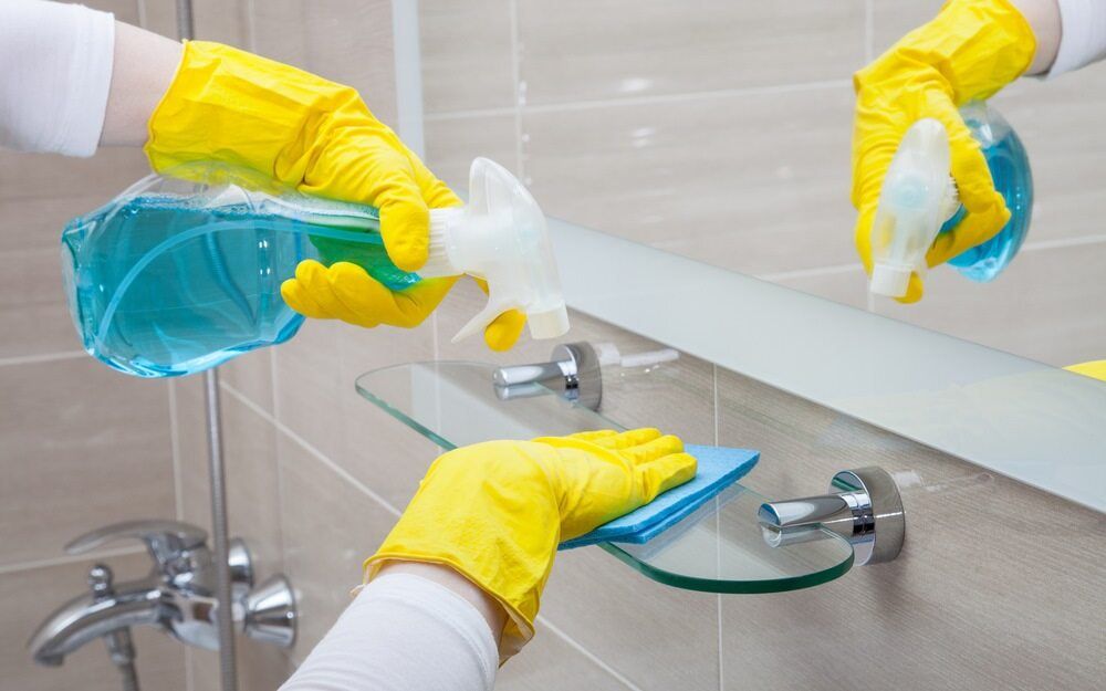 Hands in Yellow Gloves Cleaning a Bathroom Mirror  — Cleanaroo Services in Conder, ACT
