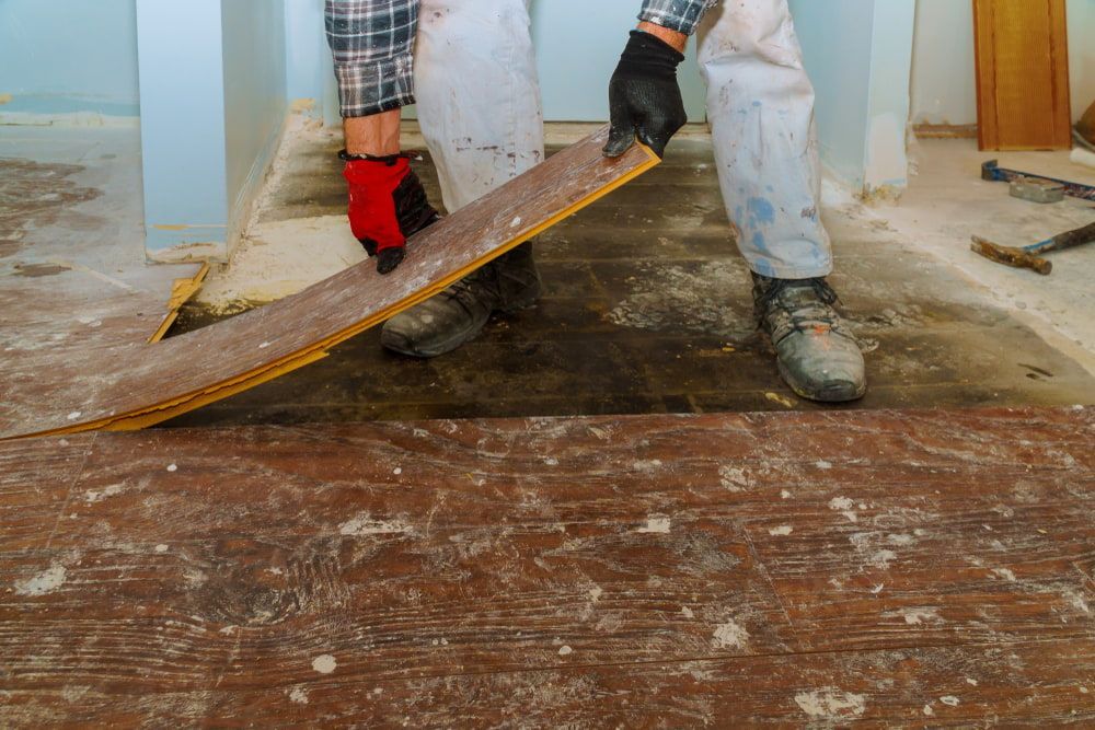 Person Wearing Gloves Removing a Damaged Wood Floor — Cleanaroo Services in Conder, ACT
