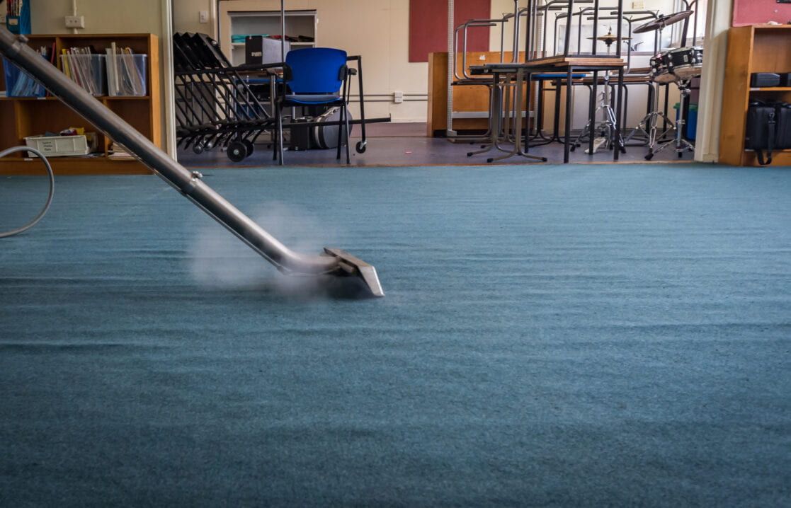 Steam Cleaner Moving Across a Blue Carpet in a Room With Shelves and Furniture — Cleanaroo Services in Conder, ACT