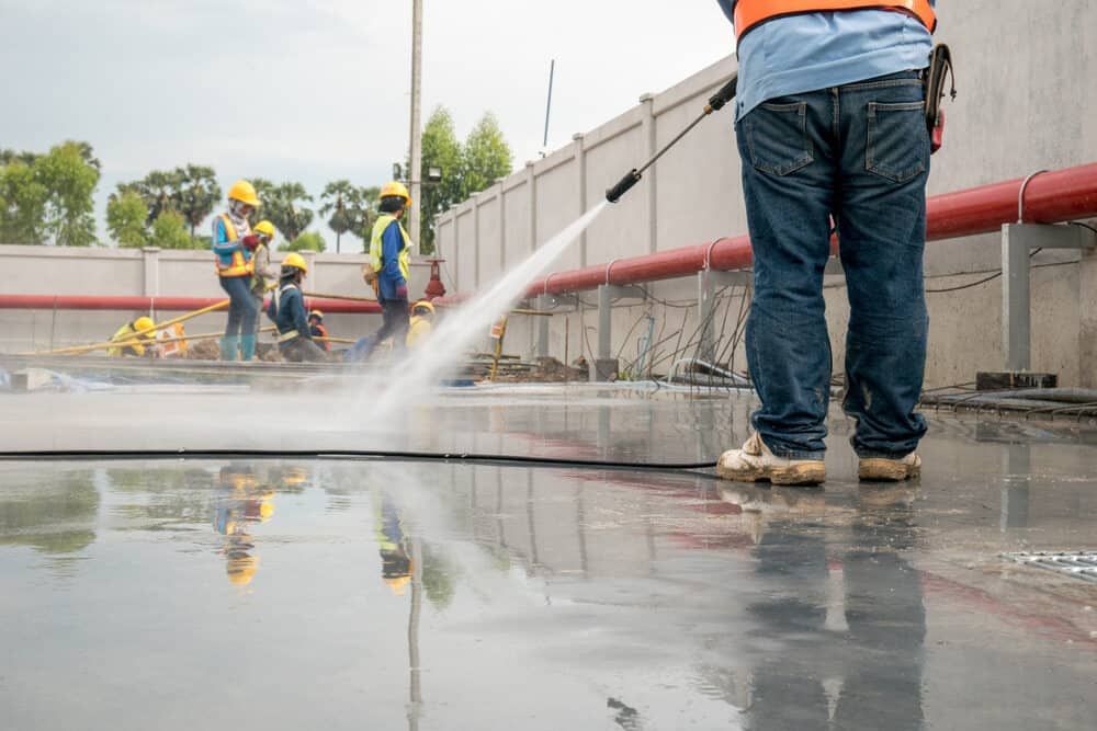 Construction Worker Using a Pressure Washer on a Gray Surface — Cleanaroo Services in Conder, ACT