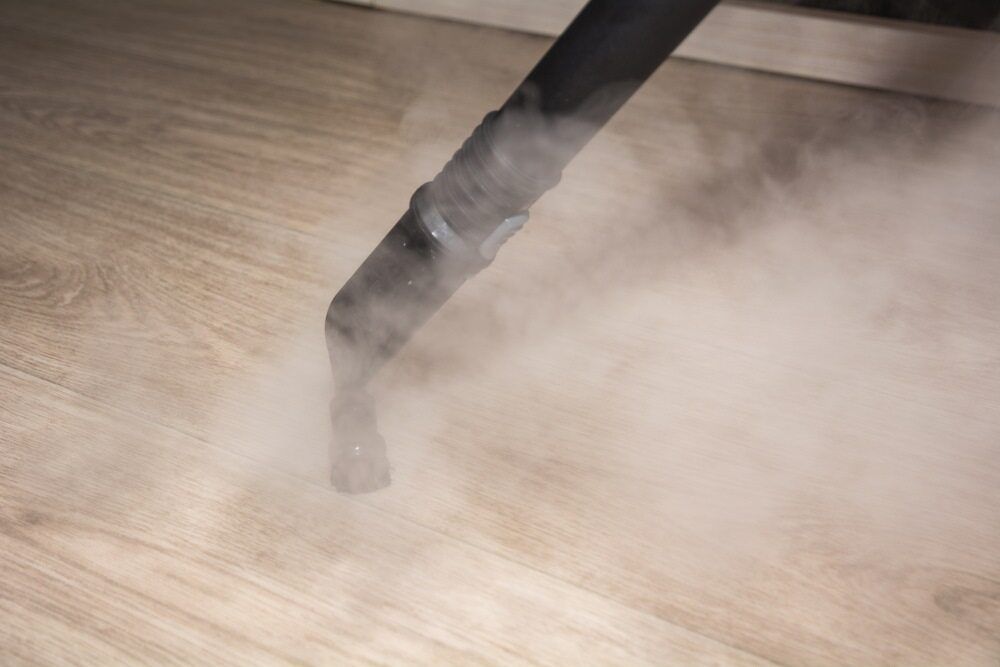 Steam Cleaner Nozzle Emitting Vapor Onto Wooden Floor — Cleanaroo Services in Conder, ACT