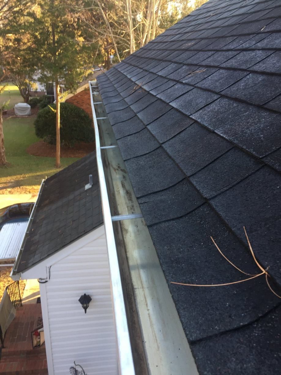 A white house with a black roof and a white gutter on it.