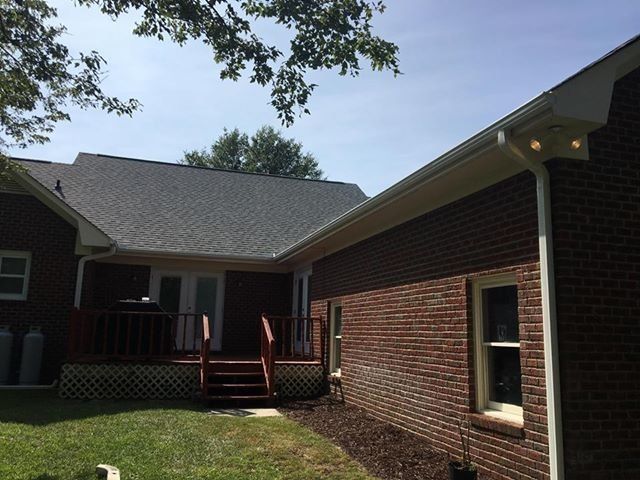 A brick house with a gray roof and a deck