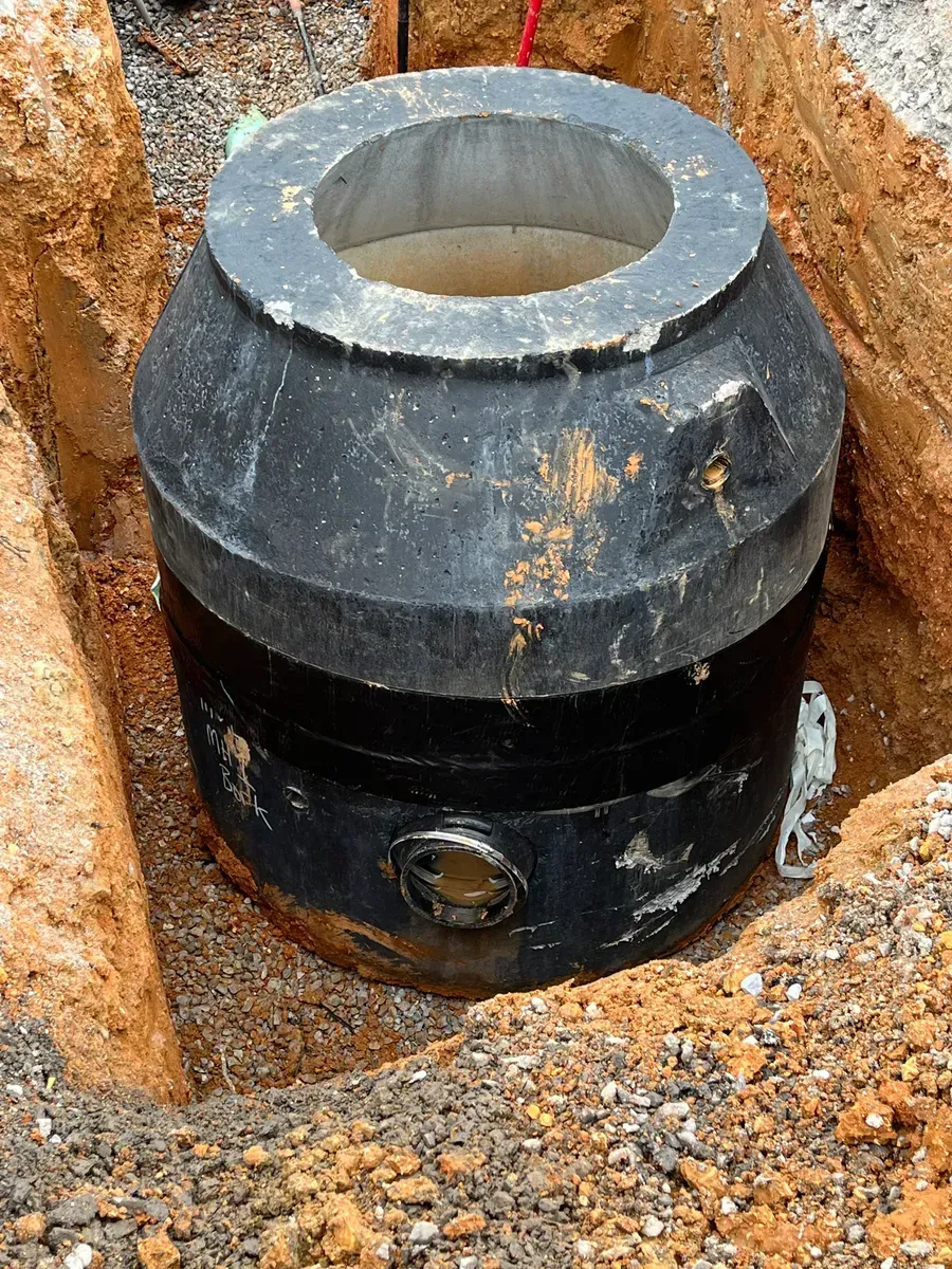 A large black object is sitting in a hole in the ground.