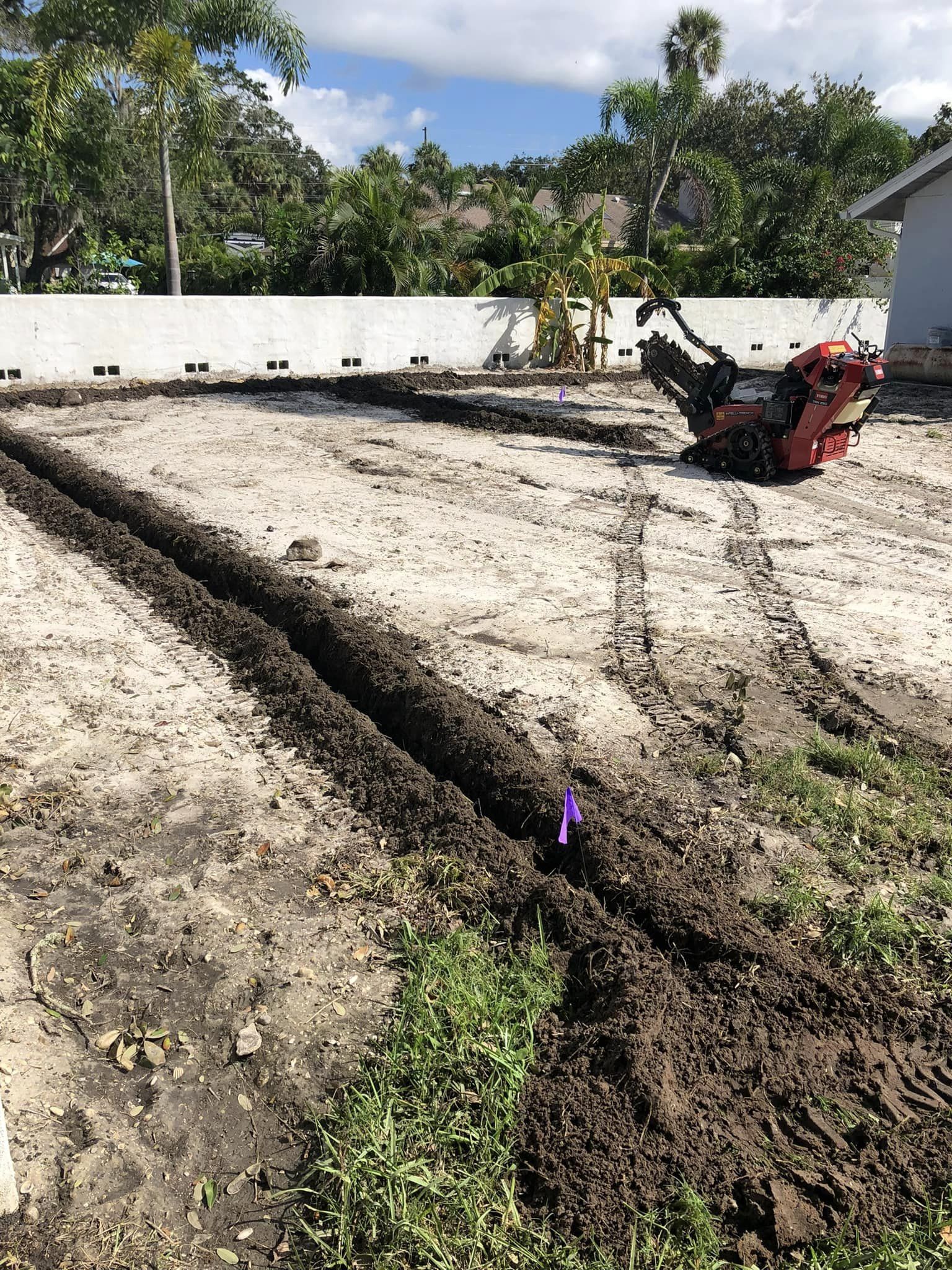 A machine is digging a trench in the dirt in a yard.