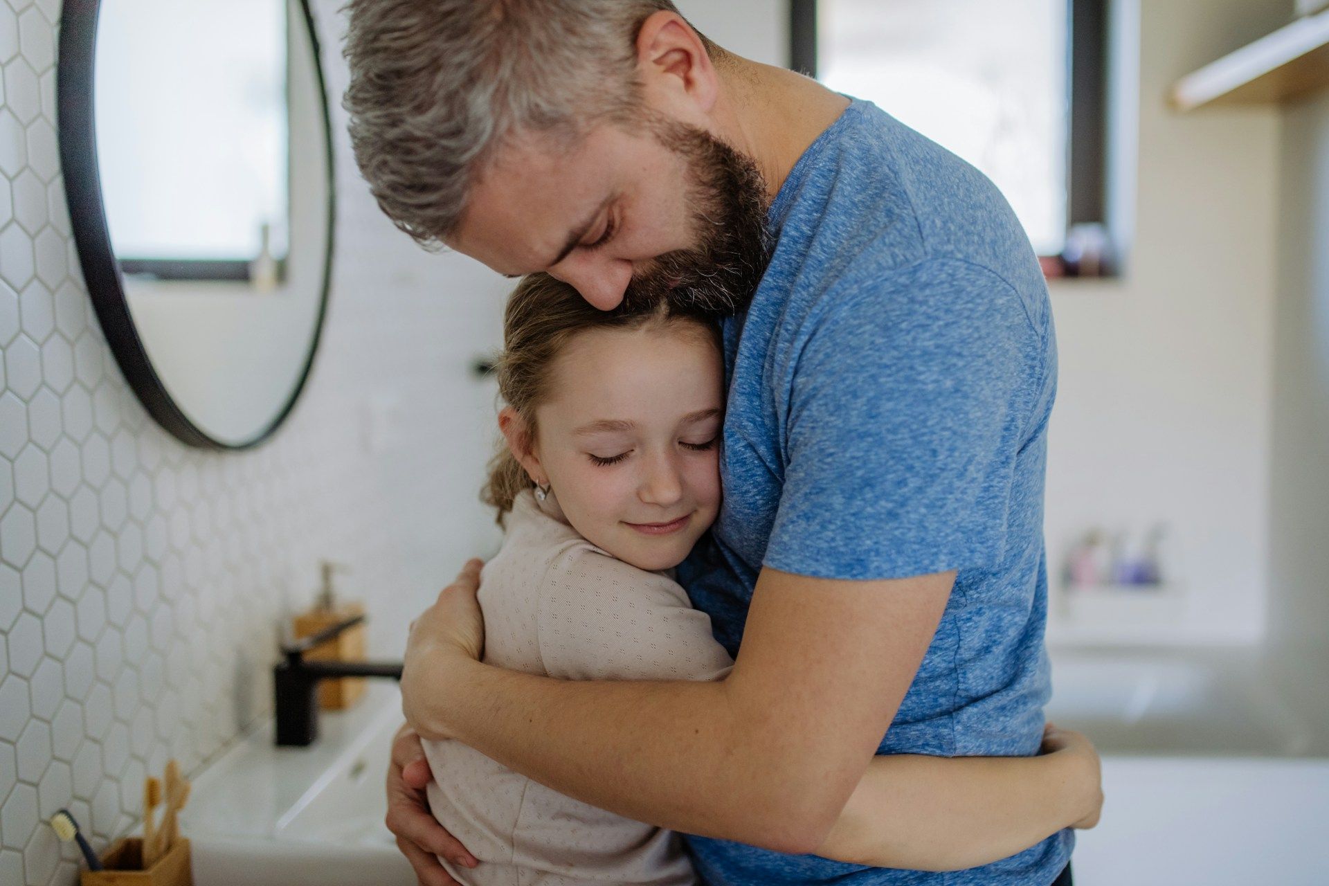 Man hugging a girl in a bathroom, close-up; both have eyes closed and appear affectionate.