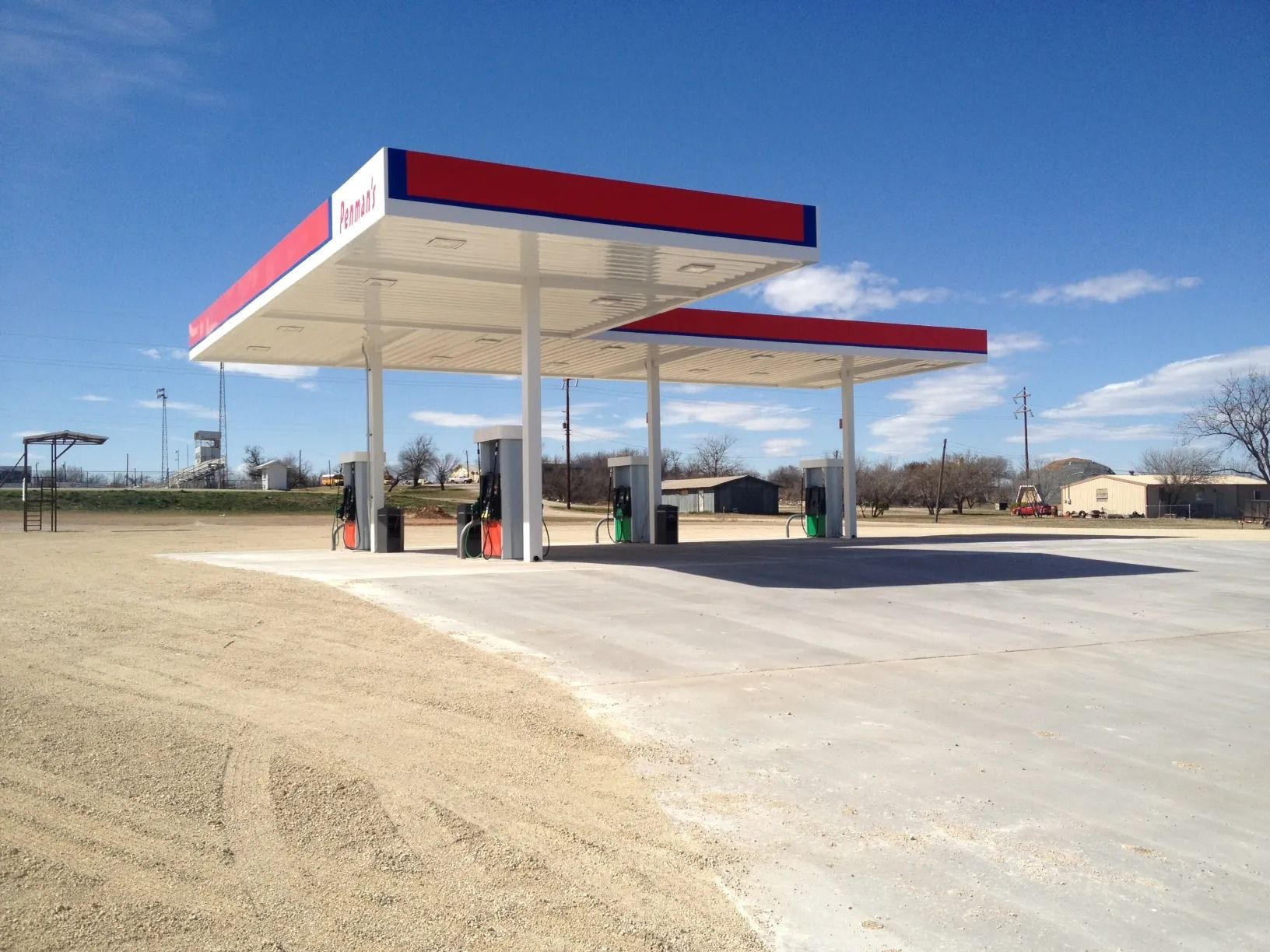 Gas station canopy with red and white roof, set in a rural area.