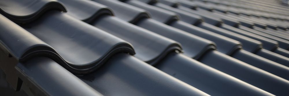A Close Up Of A Row Of Black Tiles On A Roof — Topflite Roofing In Jervis Bay, NSW