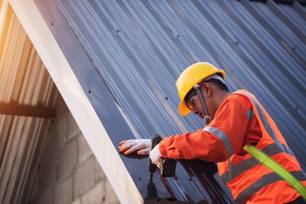 A Worker Is Installing A Metal Roof On A House— Topflite Roofing In Vincentia, NSW