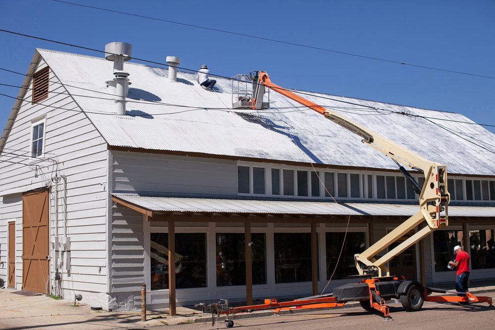 A Man Is Working On The Roof Of A Building — Topflite Roofing In Vincentia, NSW
