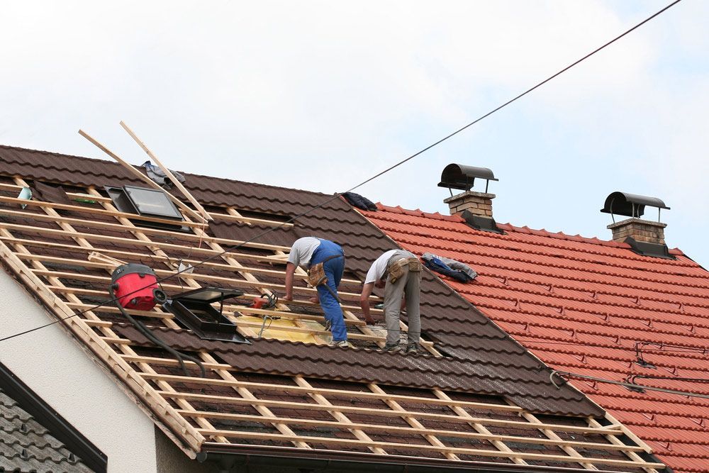 Two Men Are Working On The Roof Of A House — Topflite Roofing In Vincentia, NSW