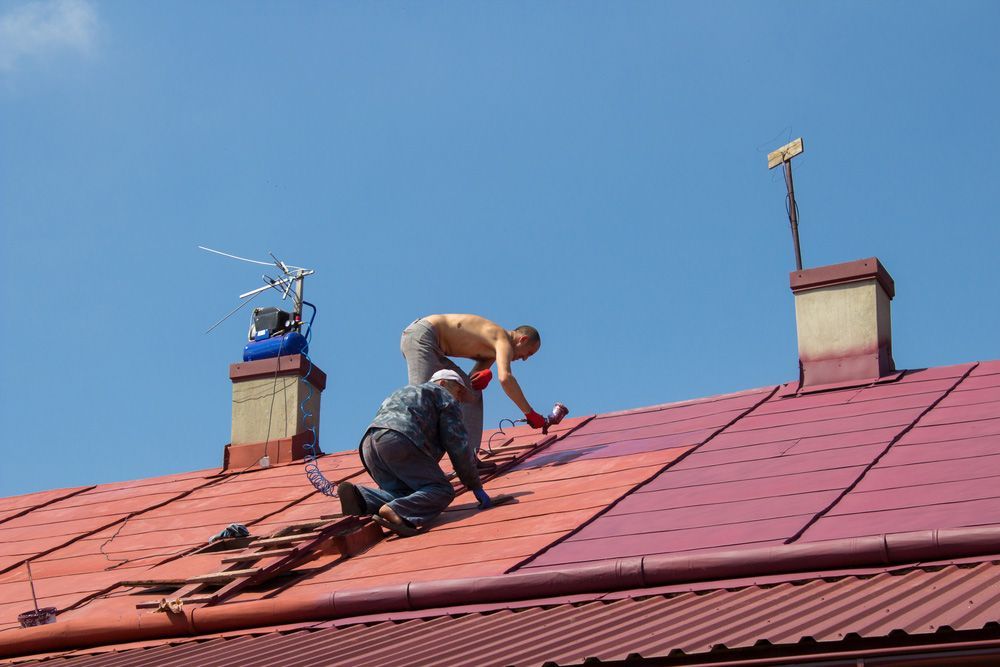 Two Men Are Working On The Roof Of A Building — Topflite Roofing In Vincentia, NSW
