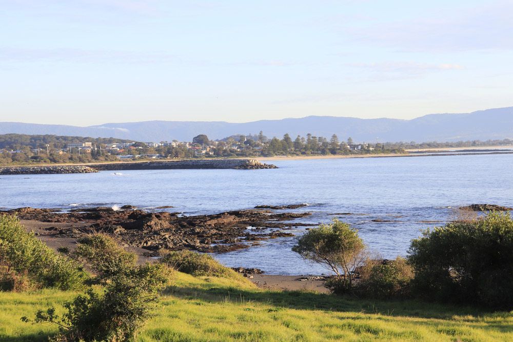 A Large Body Of Water With Mountains In The Background — Topflite Roofing In Kiama, NSW
