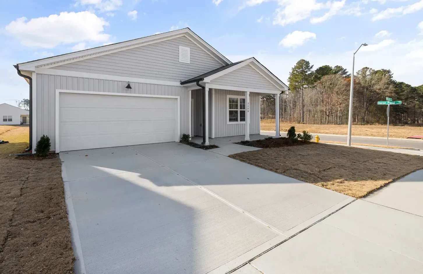 Gray house with a white garage door and a concrete driveway on a sunny day.