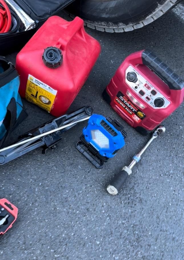A red gas can is sitting on the ground next to other tools
