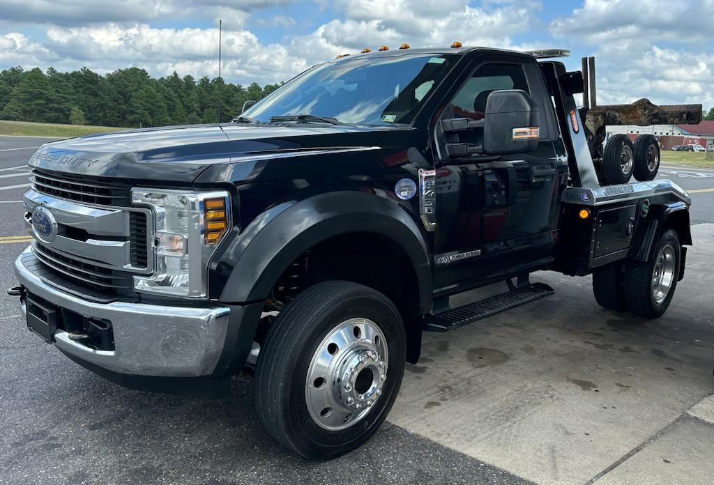 A black tow truck is parked in a parking lot.