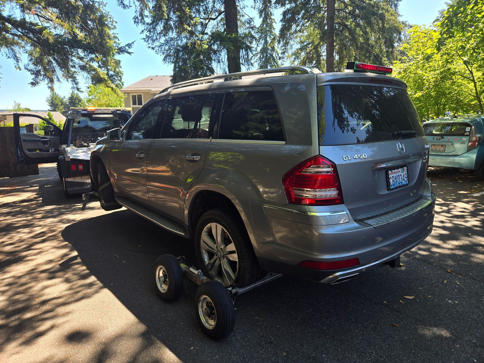 A silver suv is being towed by a trailer
