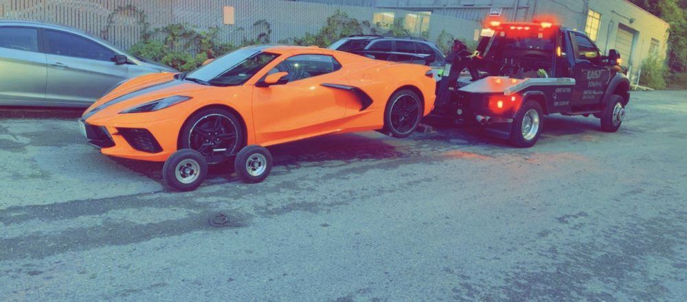 A corvette is being towed by a tow truck.