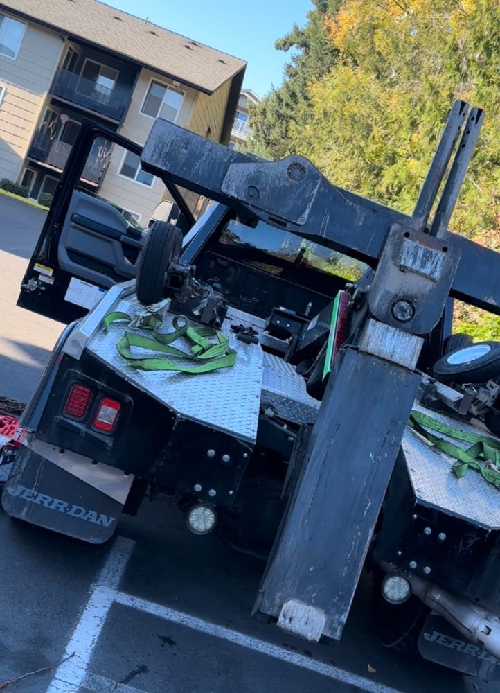 A tow truck is sitting in a parking lot next to a building.