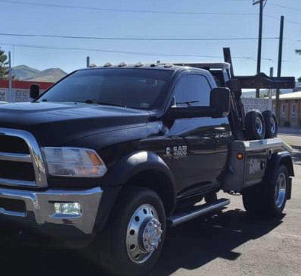 A black ram tow truck is parked on the side of the road