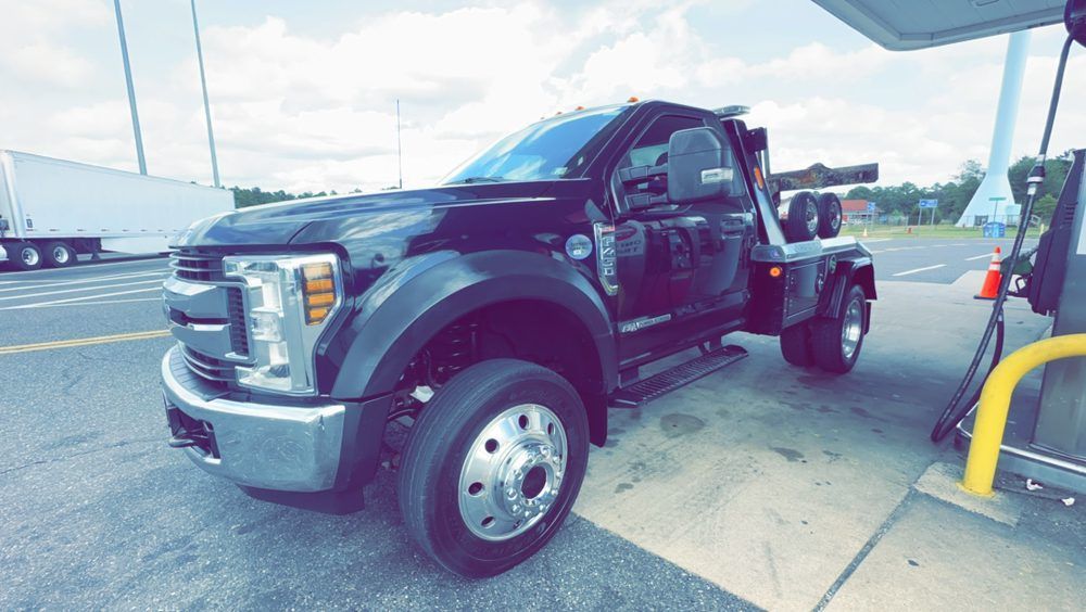 A black tow truck is parked at a gas station.