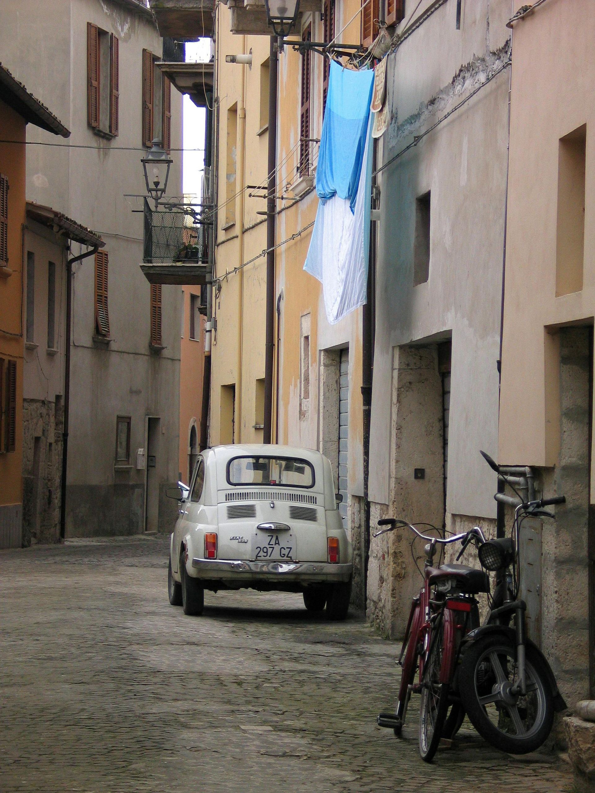 Vintage Fiat 500 and bicycle in a narrow alley of an Abruzzo village, capturing the charm, tradition, and slow lifestyle of authentic Italian towns.