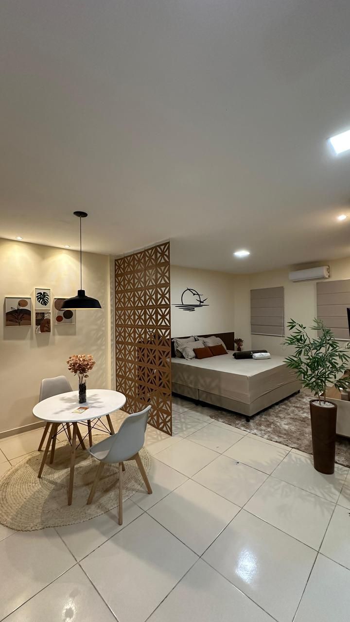 Apartamento de planta aberta com sala de jantar e quarto separados por uma divisória decorativa.