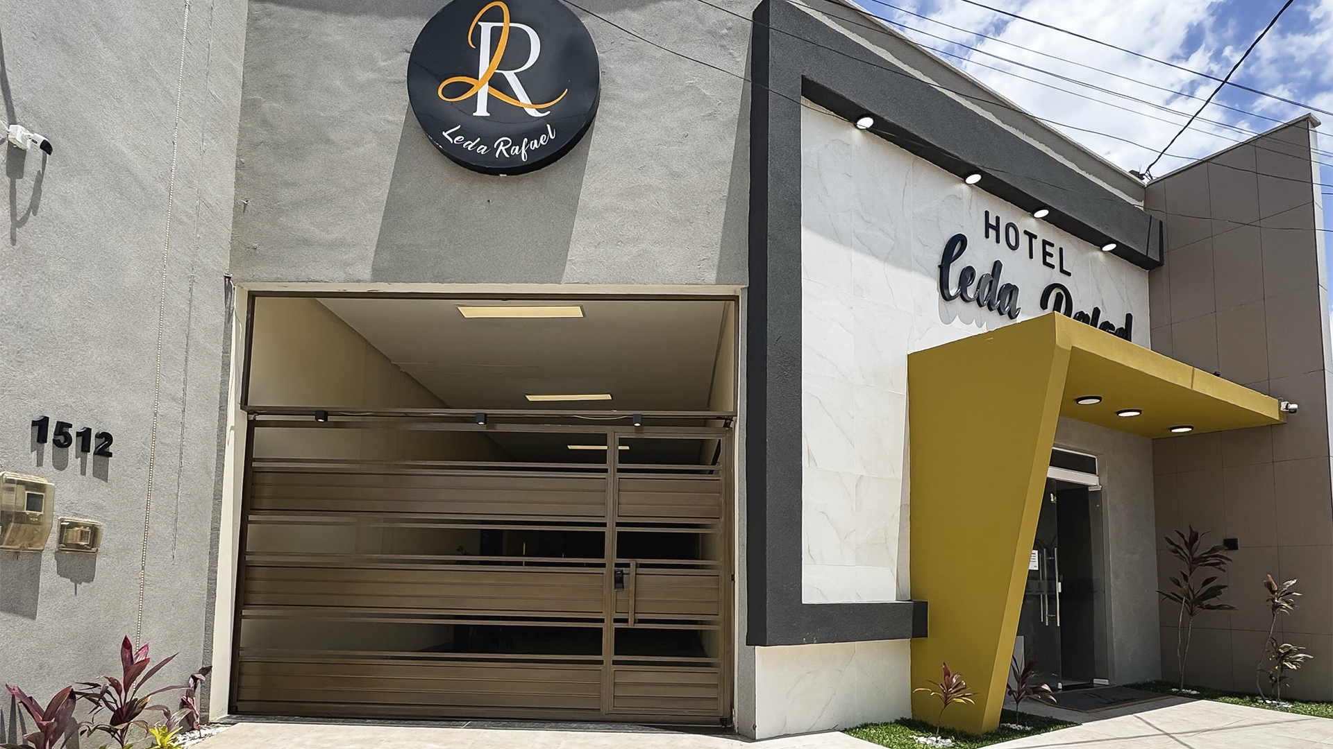 Entrada do hotel com detalhes em dourado e portão fechado.