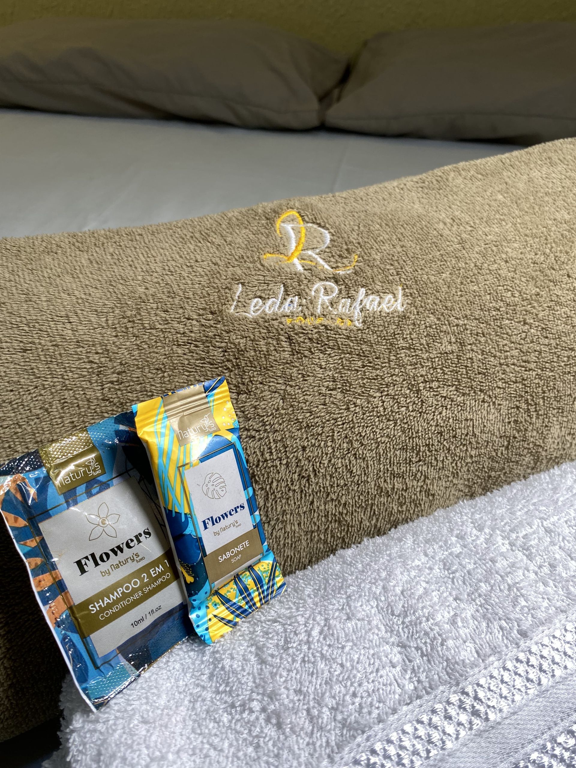 Dois pequenos pacotes de sabonete sobre uma toalha dobrada, apoiada sobre uma toalha maior.