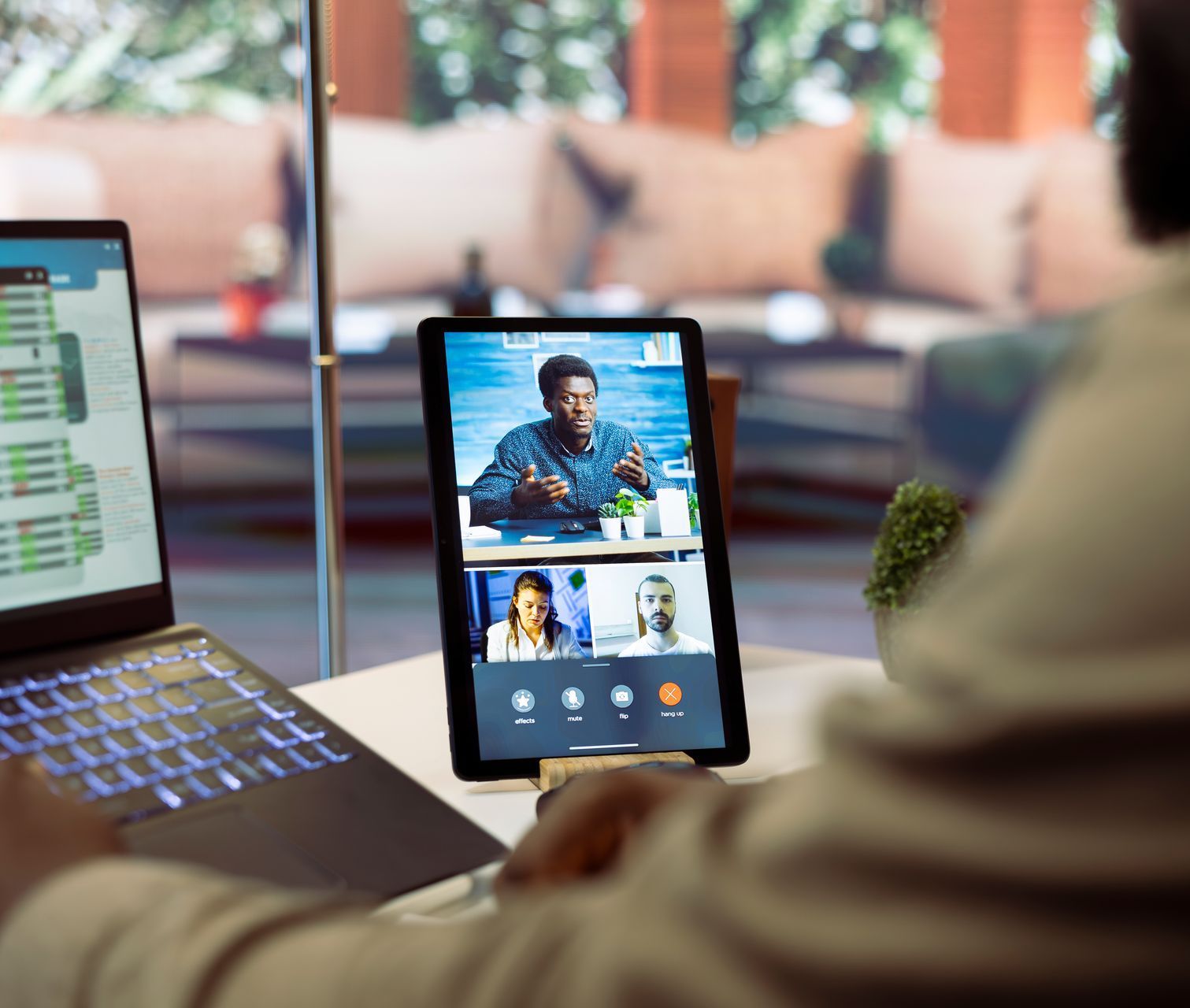 A person is sitting at a desk with a laptop and a tablet.