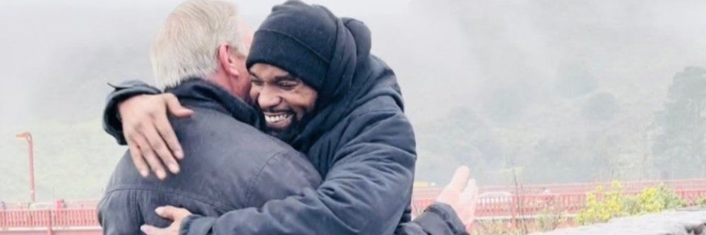 Two men are hugging each other in the rain.