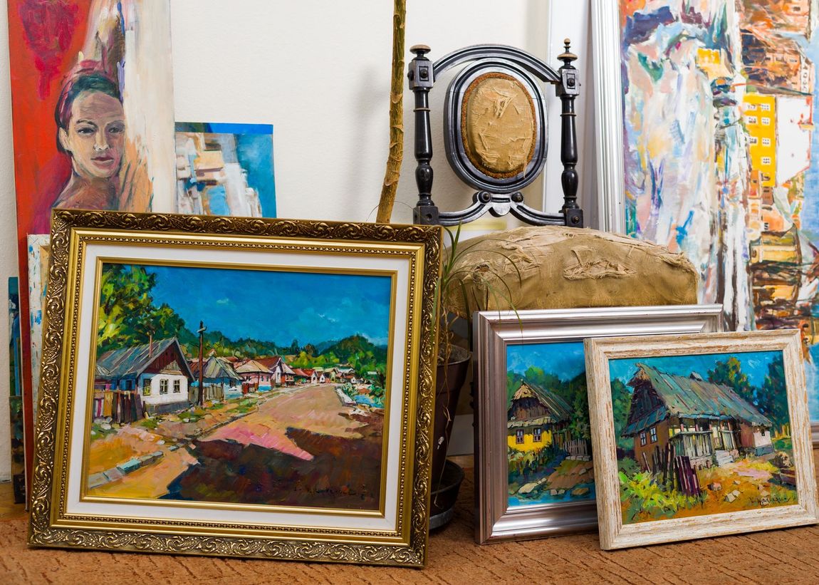 A group of paintings are sitting on a table next to a chair.