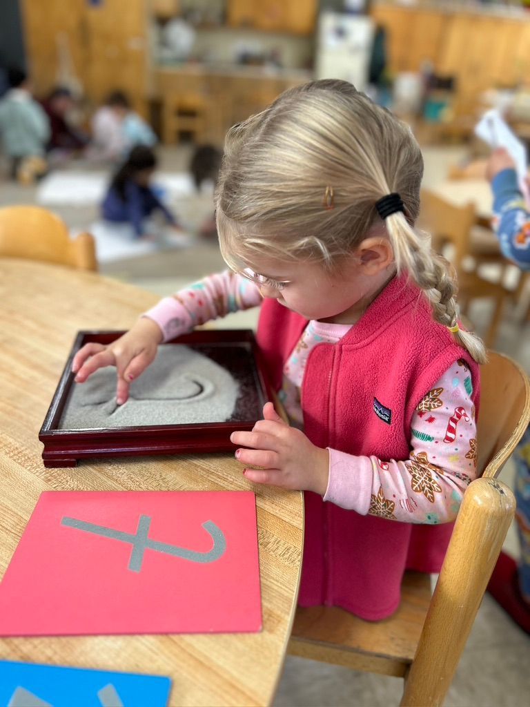 Montessori child tracing letters.