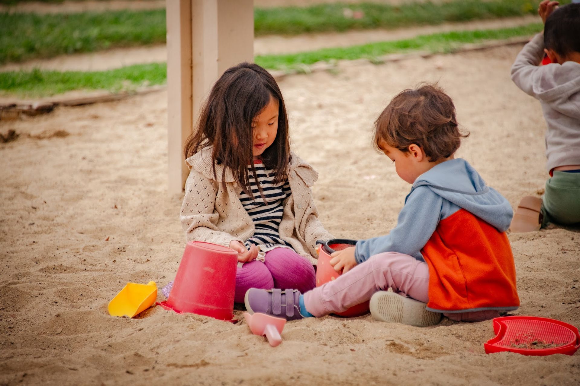 Montessori children are playing in the sand at a playground.