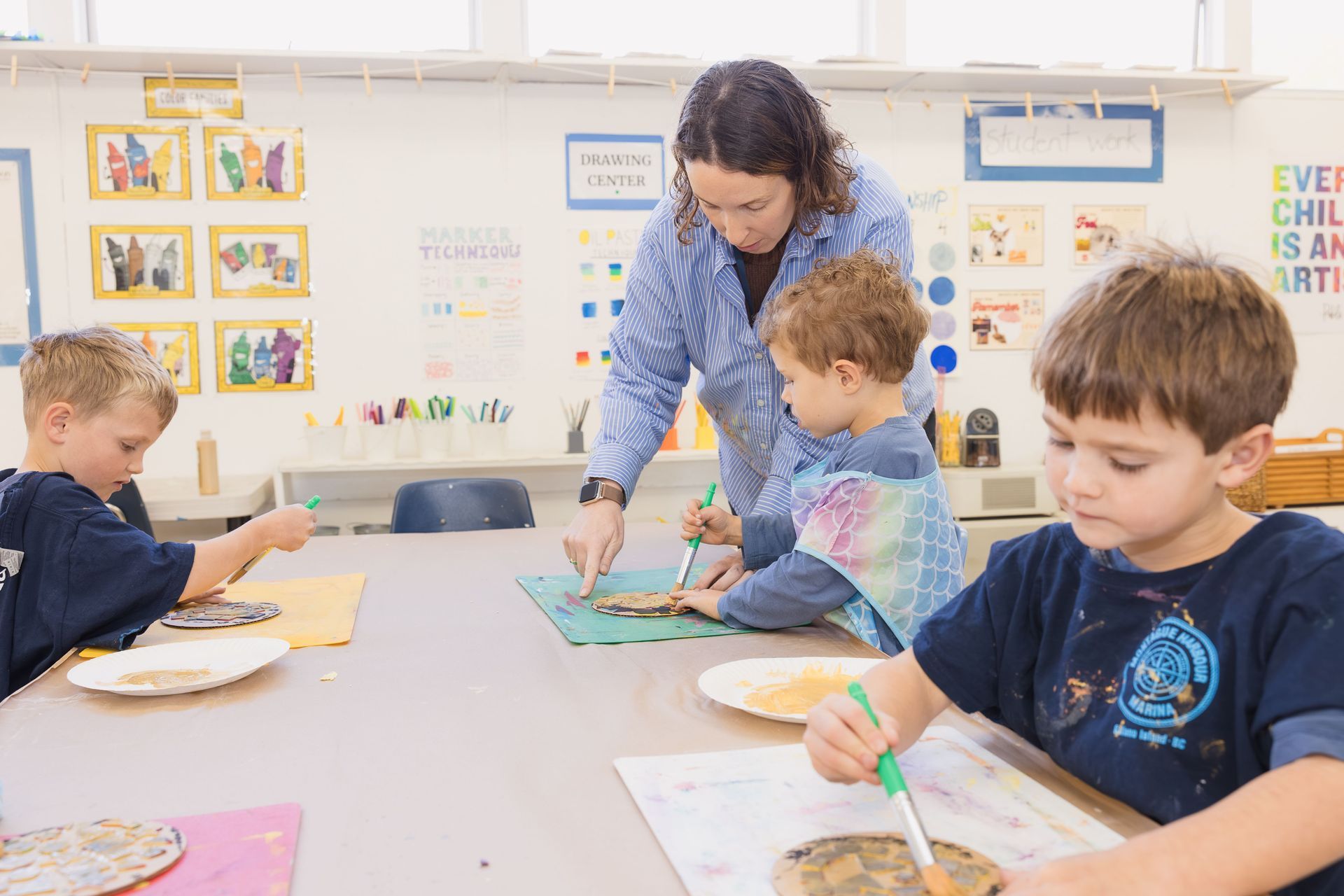 Montessori gude assisting a child with an art project