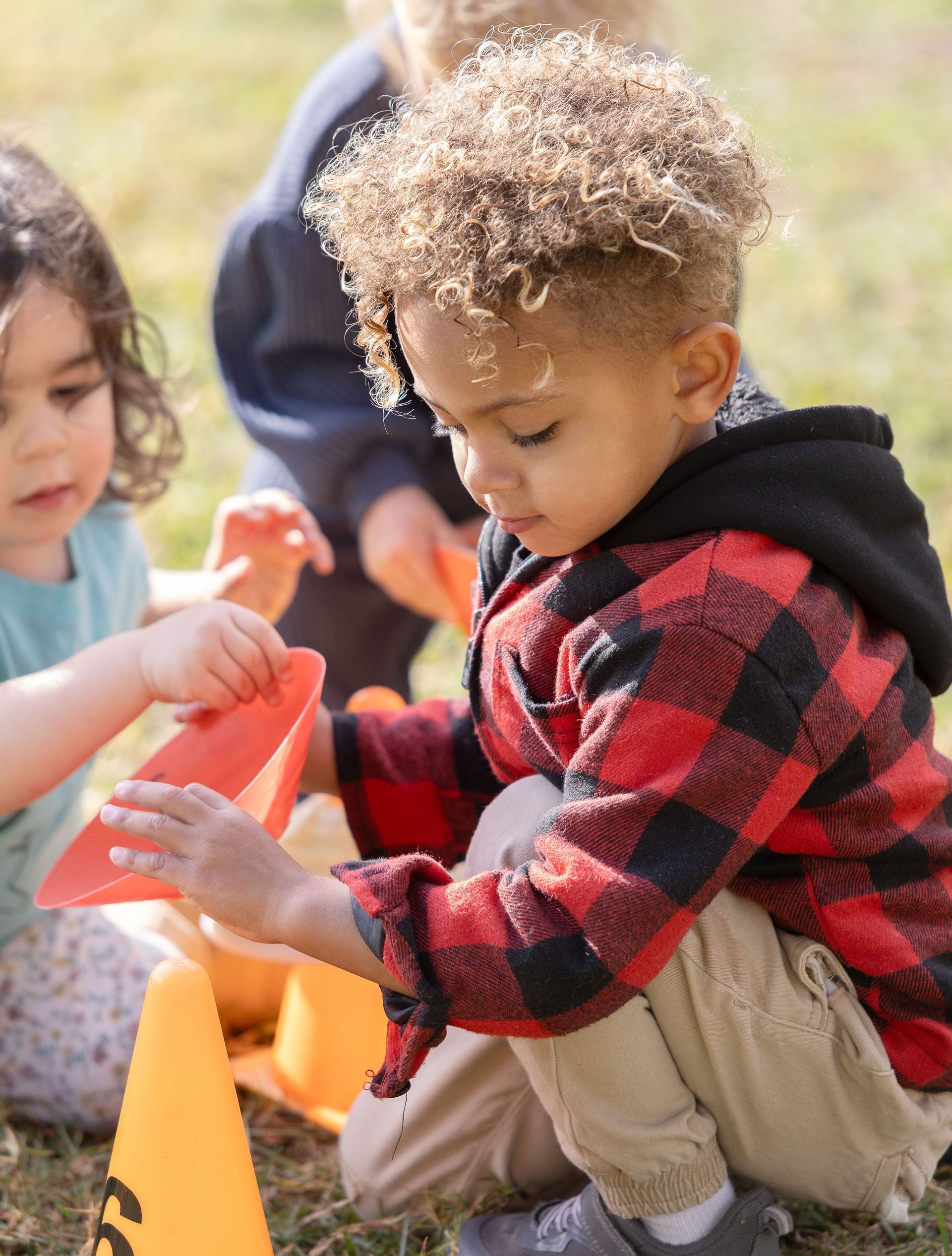 Montessori children are playing with cones in the grass.