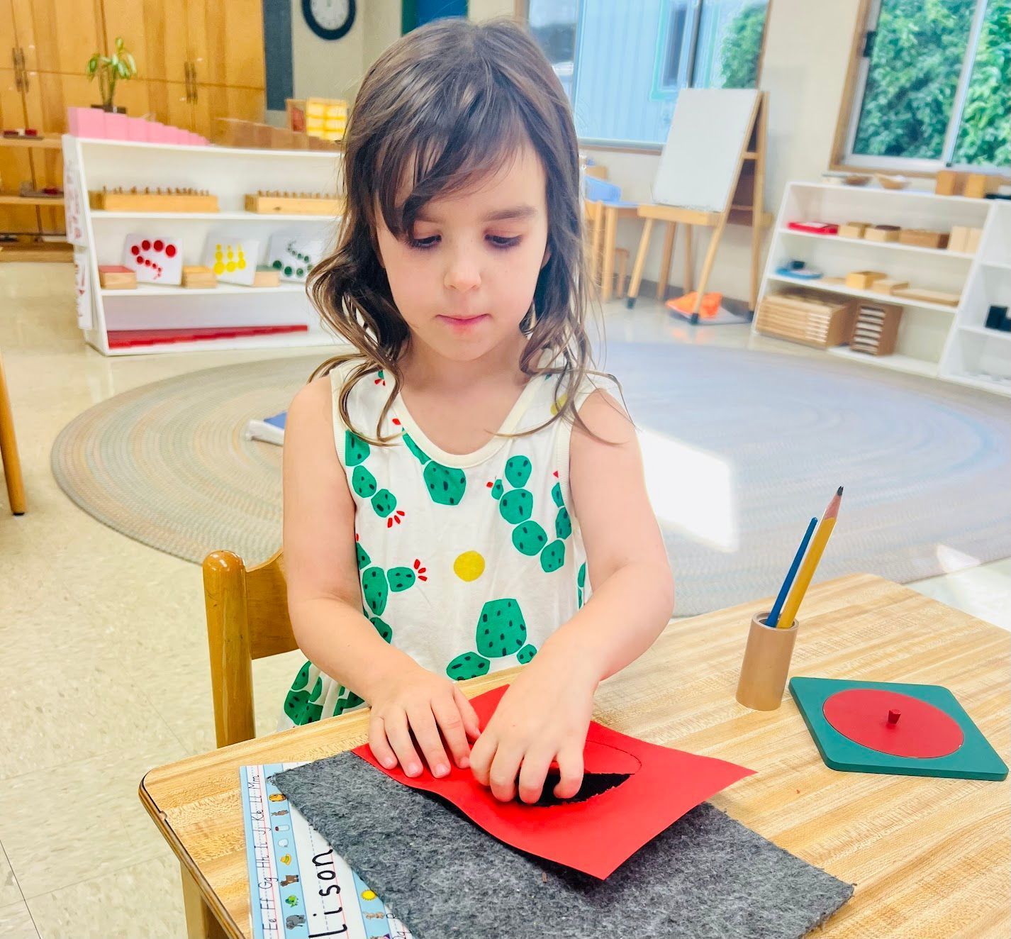 A montessori child is sitting at a table working with math materials.