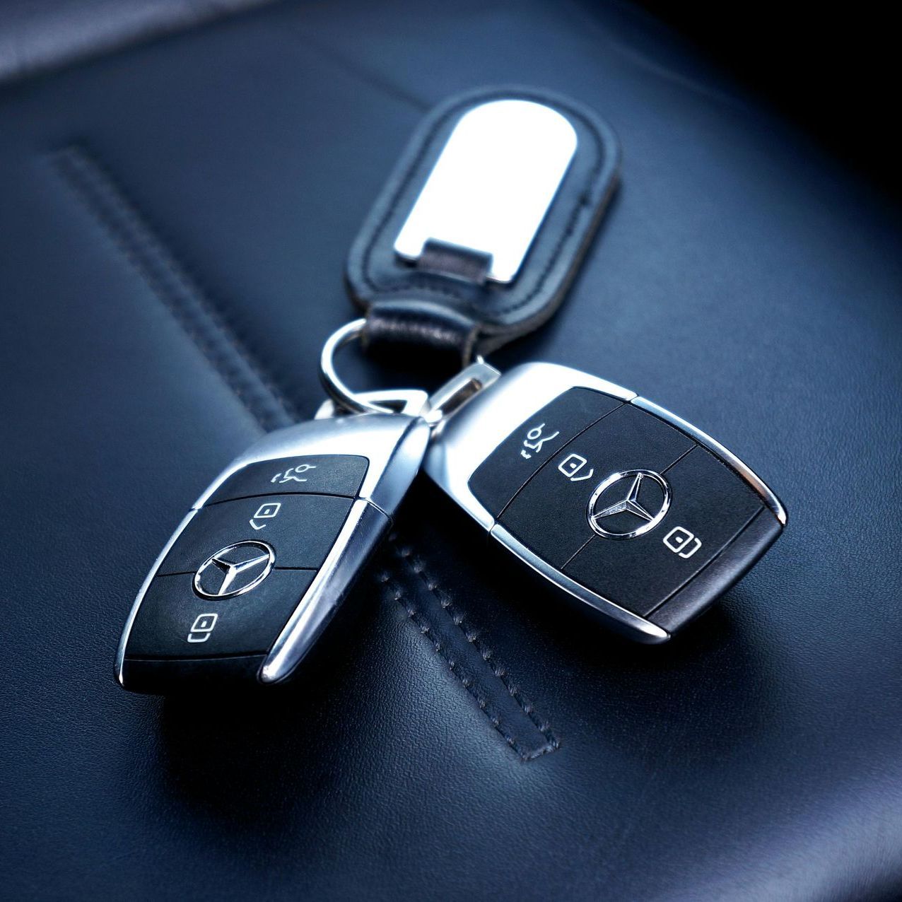 Jeu de clés de voiture mercedes avec porté clé, posé sur un siège de voiture de couleur noir