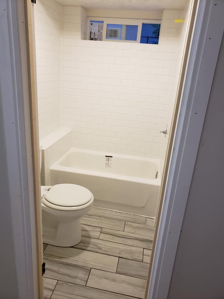 A bathroom with a toilet , tub and shower.