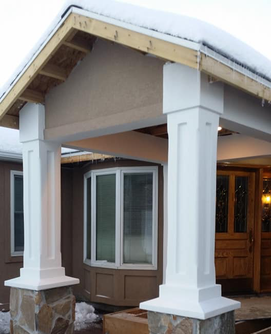 A brown house with white columns and a window