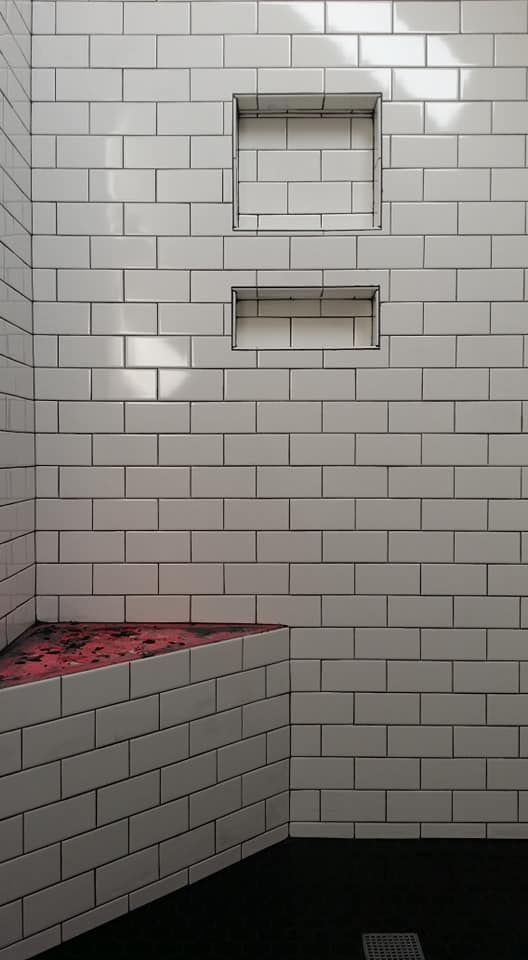 A shower with white tiles and a red seat