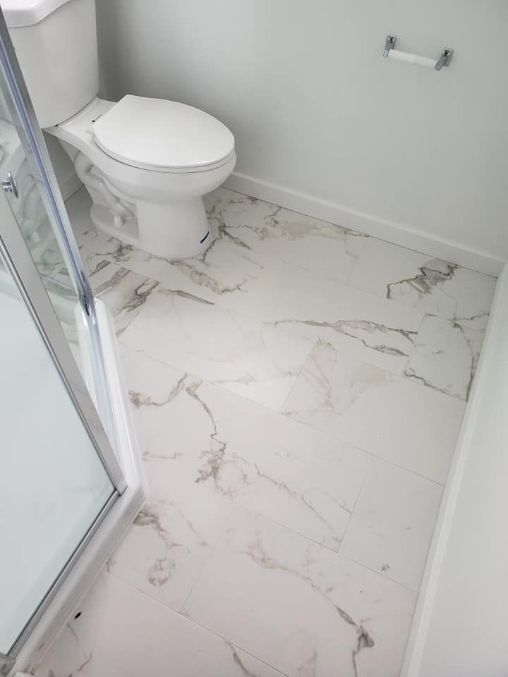 A bathroom with a toilet , shower and marble floor.
