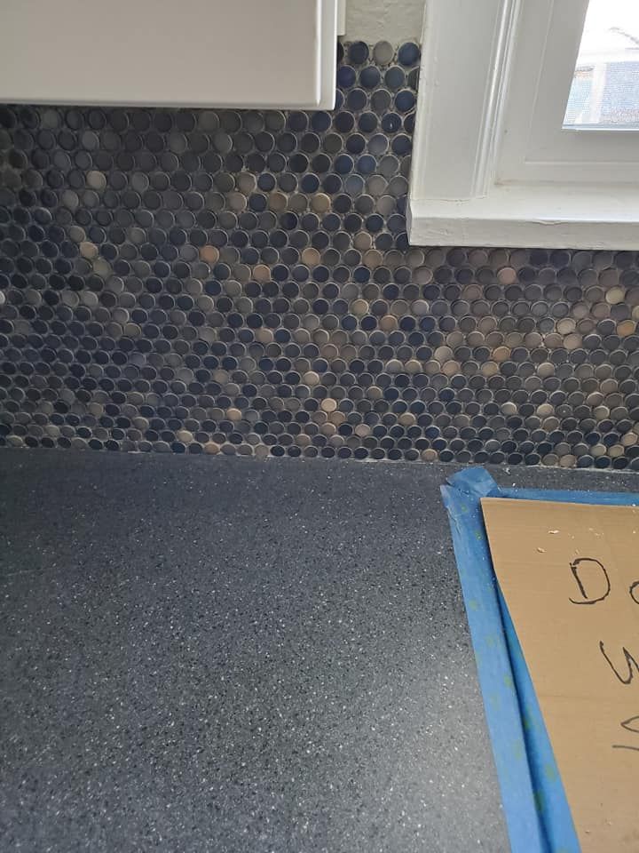 A kitchen counter with a tile wall and a window.