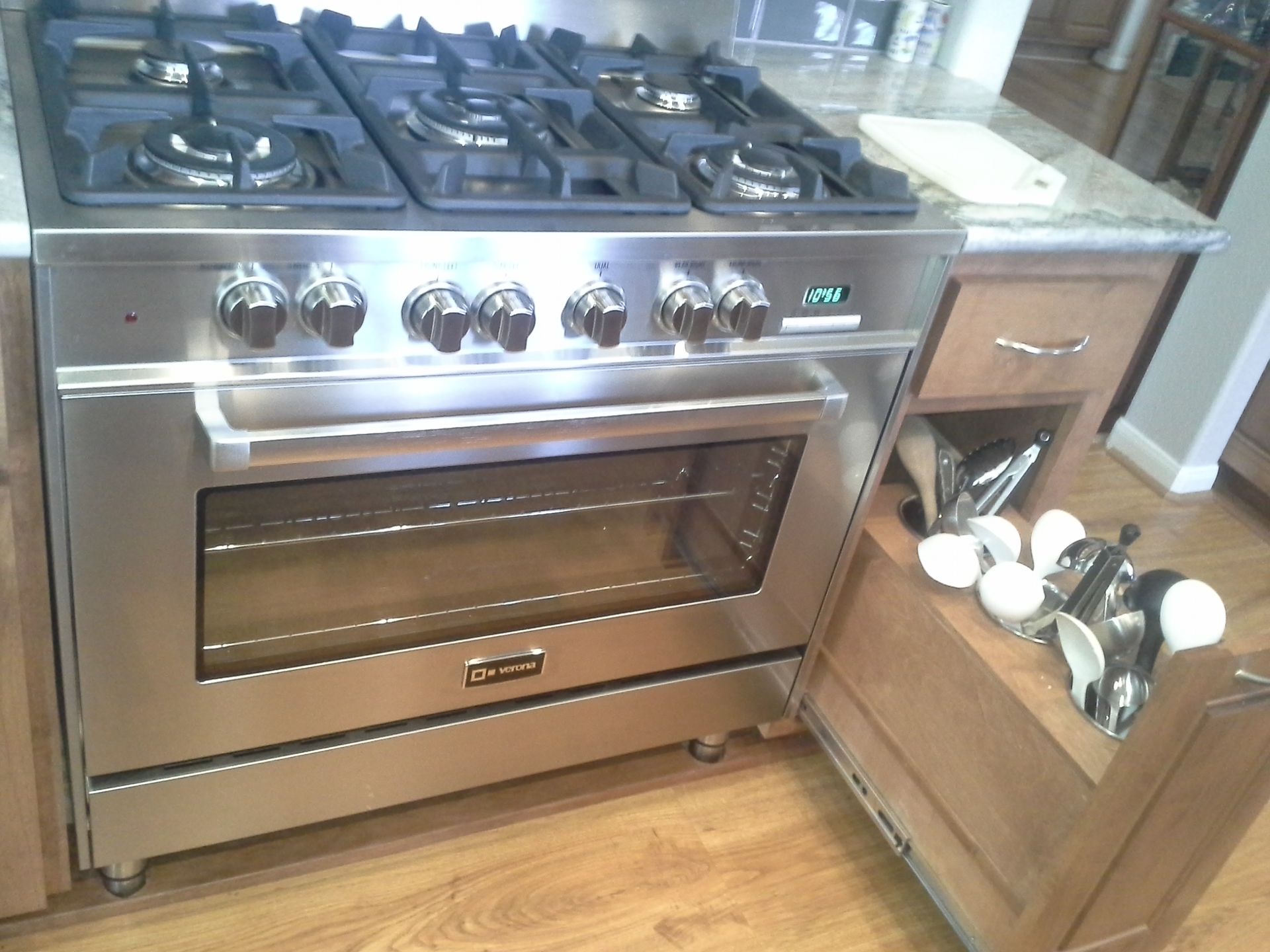 A stainless steel stove in a kitchen with a pull out drawer