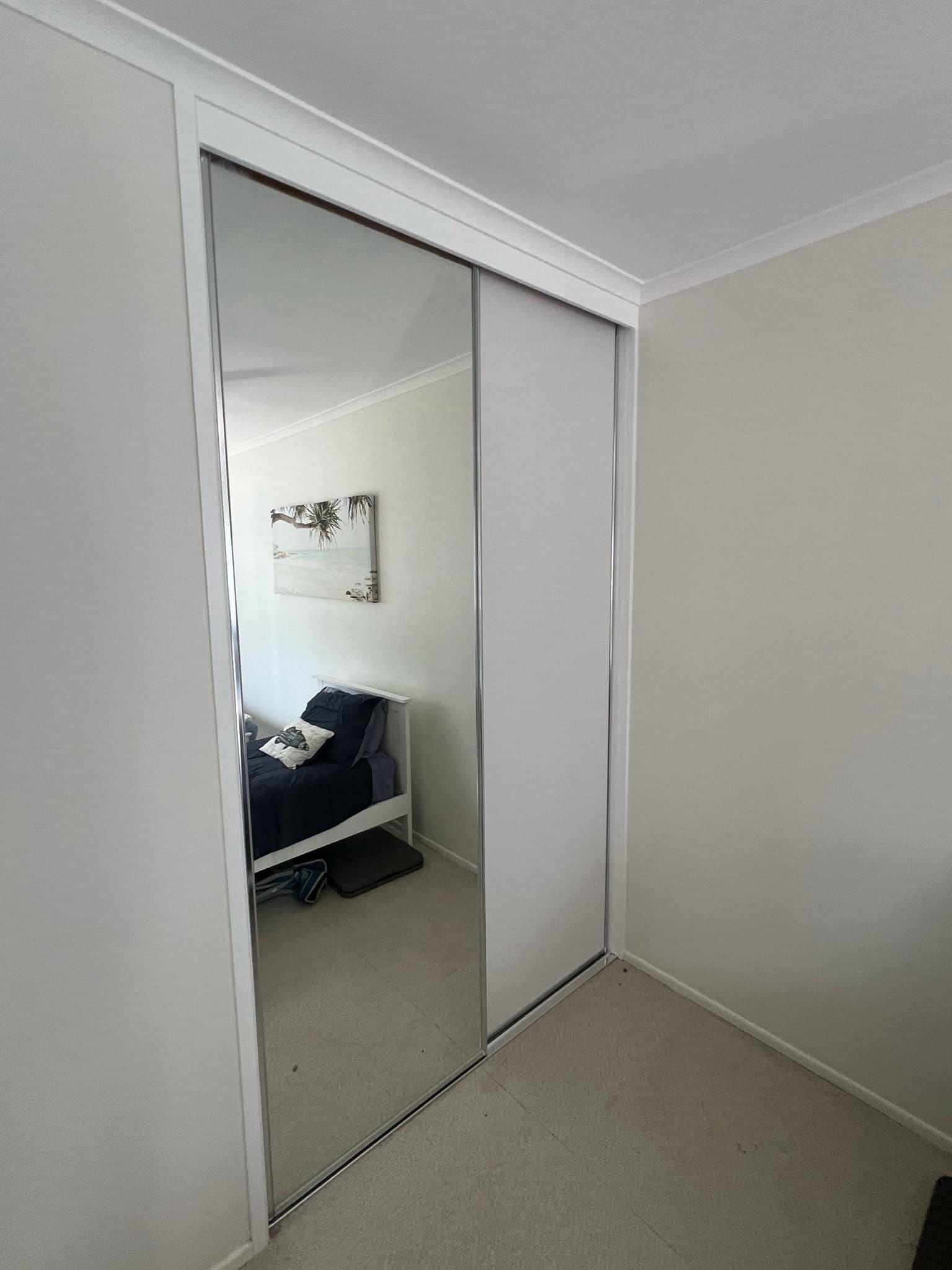 A Bedroom With Mirror Sliding Doors And A Bed — Advantage Screens and Blinds Hervey Bay In Pialba, QLD