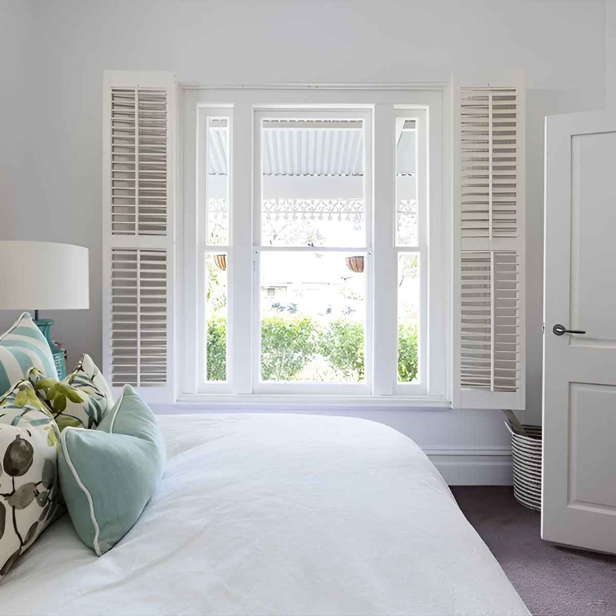 A Bedroom With A Bed And A Window With Shutters — Advantage Screens and Blinds Hervey Bay In Pialba, QLD