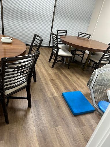 Wooden tables with chairs on a wood floor, blue foam pad in the center.