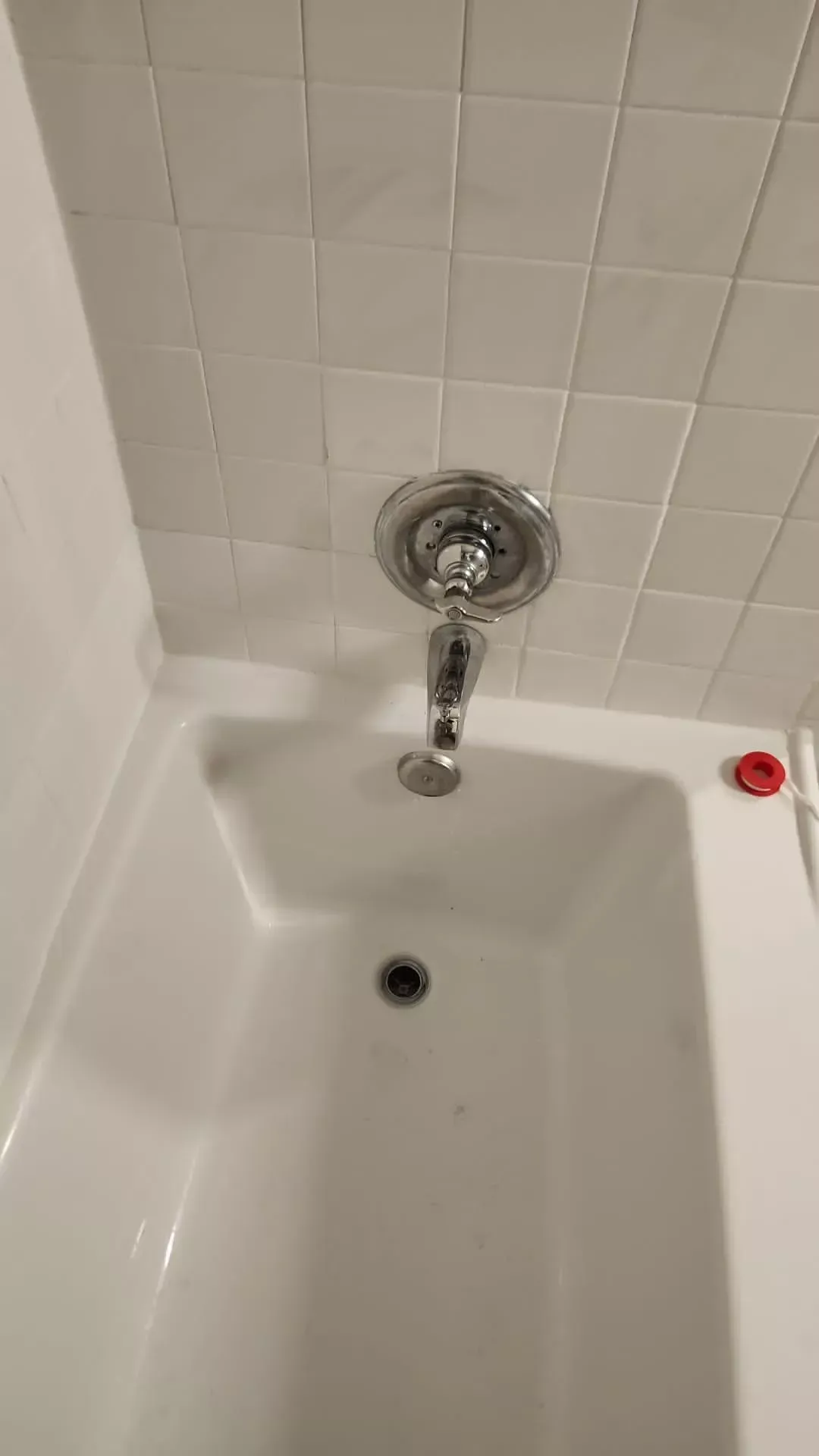 White bathtub with showerhead and faucet against tiled wall.