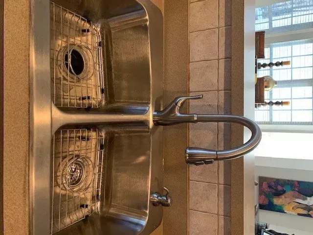 A stainless steel kitchen sink with a faucet in a kitchen.