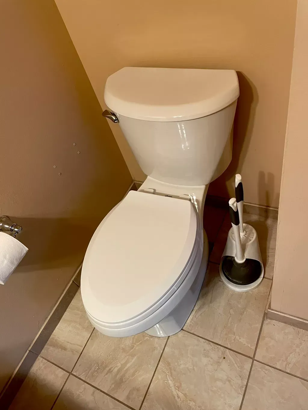 A toilet with a toilet brush next to it in a bathroom.